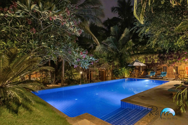 Pool corner lit at night with trees behind.
