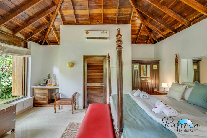 Canopy bed with red bench and wood-beamed ceiling in the Louvre Cottage.