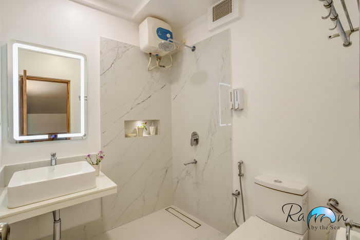 White tiled bathroom with shower, sink, and water heater