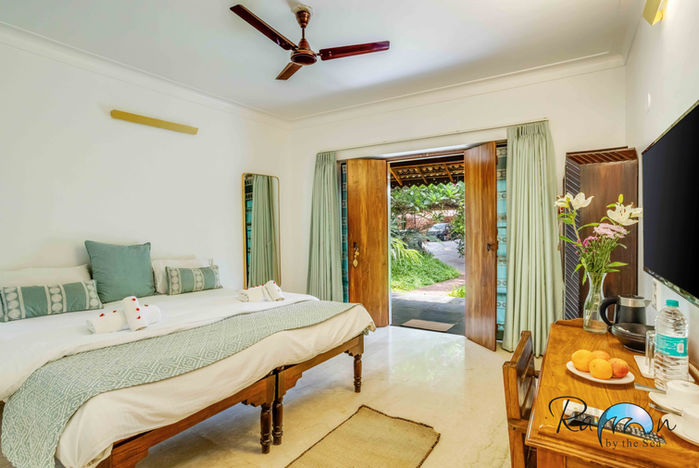 Room interior with bed facing open doors leading to garden path