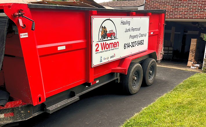 A dumpster backed up to a garage for garage cleanout service in Columbus by 2 Women With A Pickup Truck And Trailer Too LLC