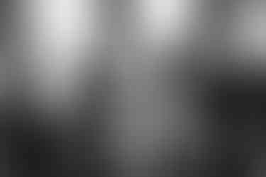 The bride and groom listen to the officiant speak during the ceremony. In black and white.