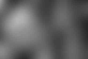 The groom speaks to a guest as they both smile, in black and white.