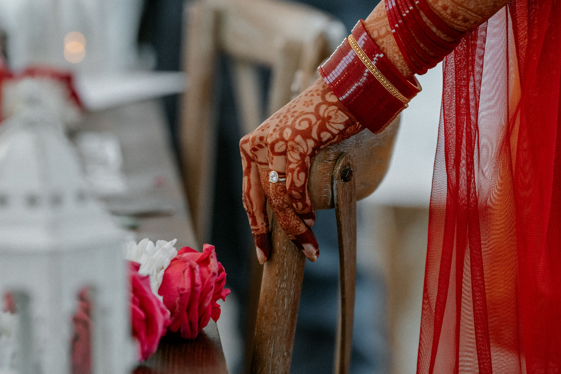 A close up of the brides hand and her wedding ring, her hand rests on a chair.