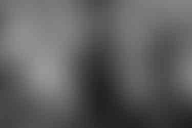 The officiant smiles and points at a seat during dinner in black and white.