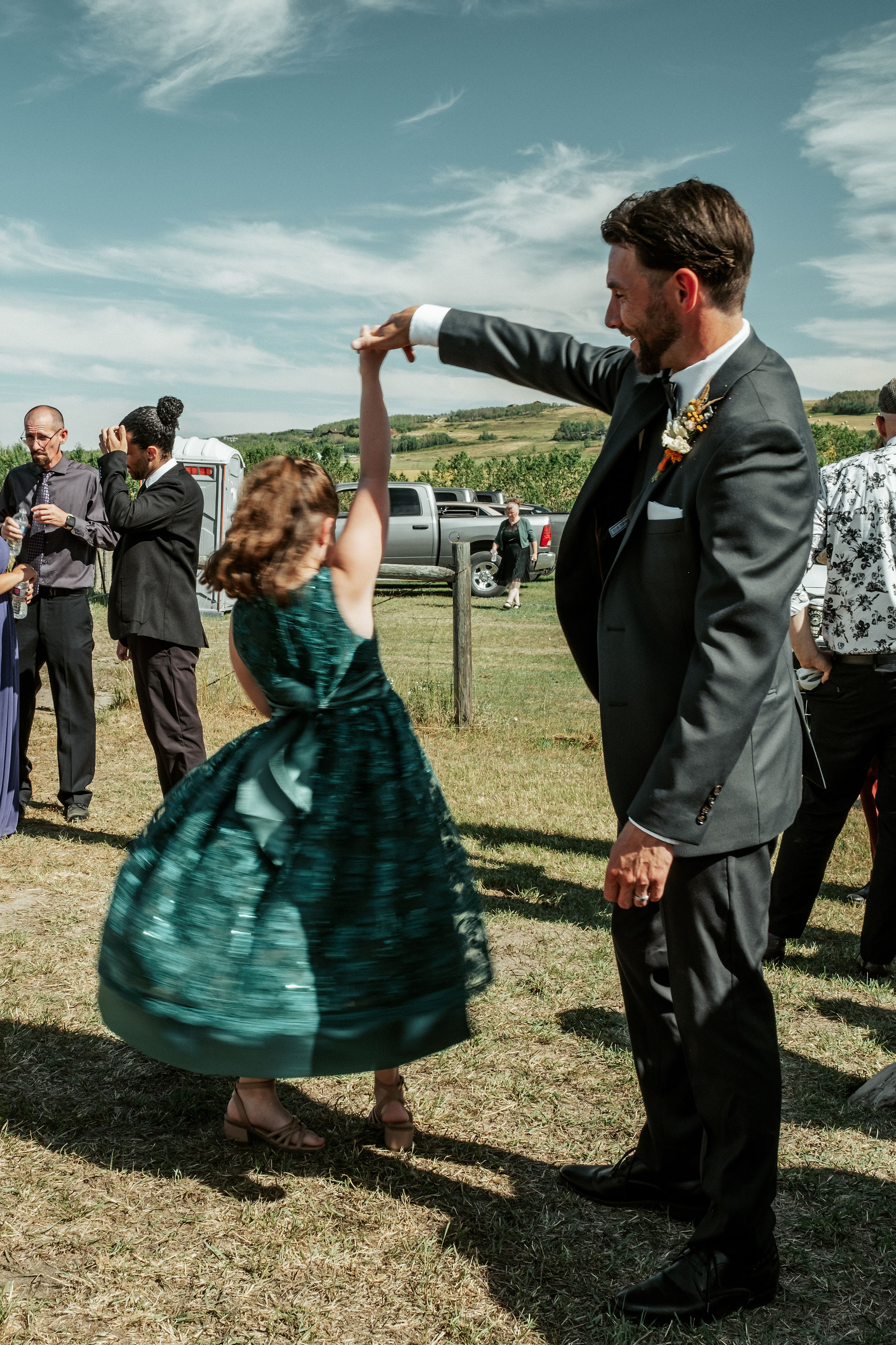 The groom spins a young guest in a green dress.