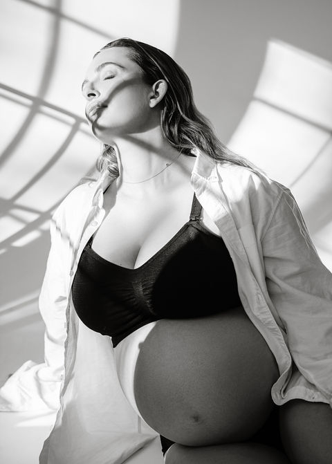 Studio Maternity Photography Portfolio in Portland, Maine with photo of a pregnant woman posing in a black bra and white shirt