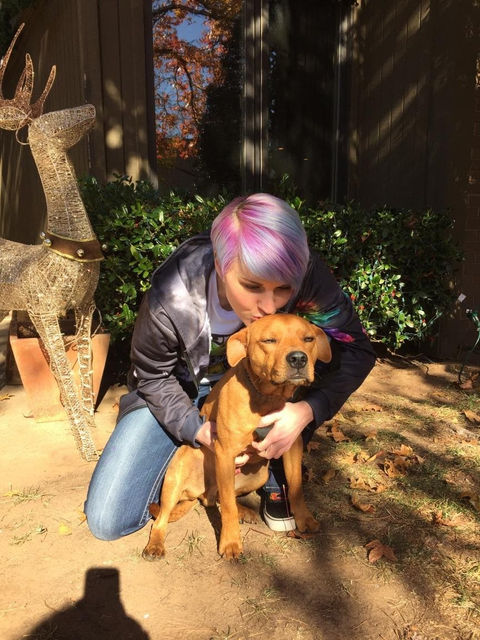 Woman kissing dog on top of the head