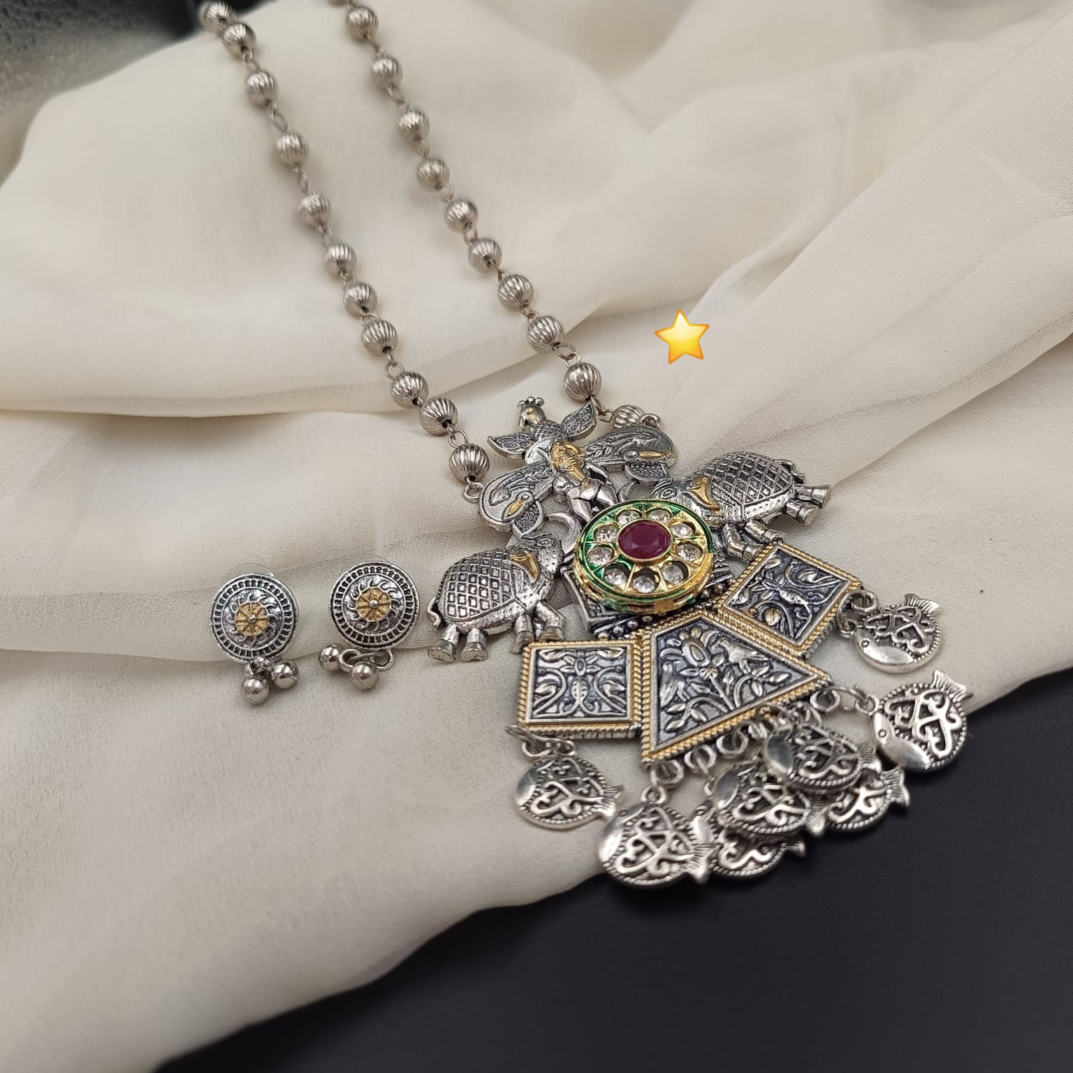 Vintage silver tone necklace set displaying an intricately carved centerpiece and dangle earrings.