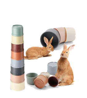 Two brown rabbits playing with colorful stacking cups.