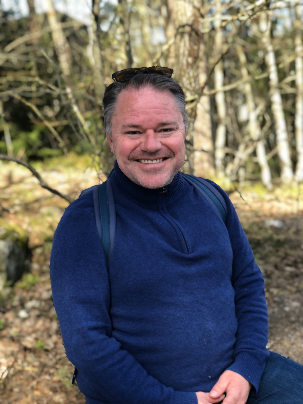 Anders M. Tangen holder på med noe. Å sitte på en stubben.