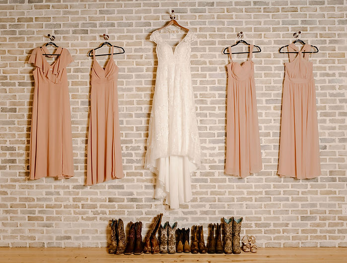Bride’s dress and bridesmaids' dresses hanging in The Celebration Barn’s bridal suite