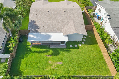 Aerial drone shot displaying the backyard area, featuring outdoor space and landscaping details.