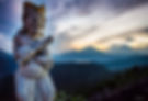Sunrise over the volcanoes with Balinese statue in the foreground.