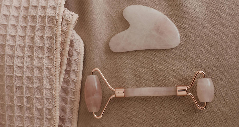 Egy rózsaszín hagyományos két végű arcroller és egy gua sha fekszik egy bézs színű törölköző mellett