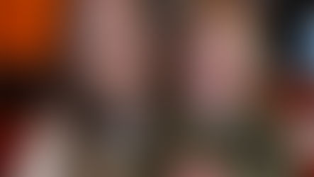 A mum and her toddler sitting at a pizza restaurant table in a warmly lit restaurant with orange walls. Both smiling, creating a joyful mood.