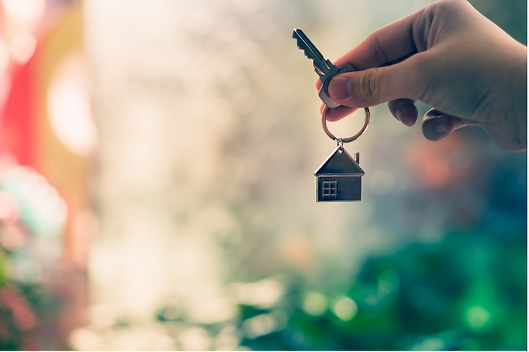 Hand holding a key with a house keychain.
