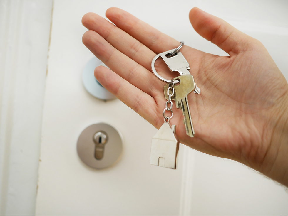 Hand holding keys to apartment with a house keychain