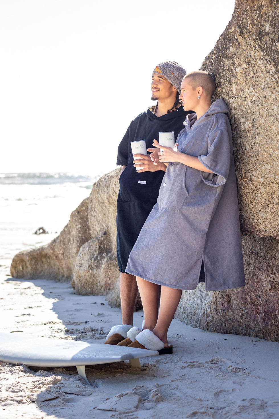 couple with travel flasks at the beach on a cold morning