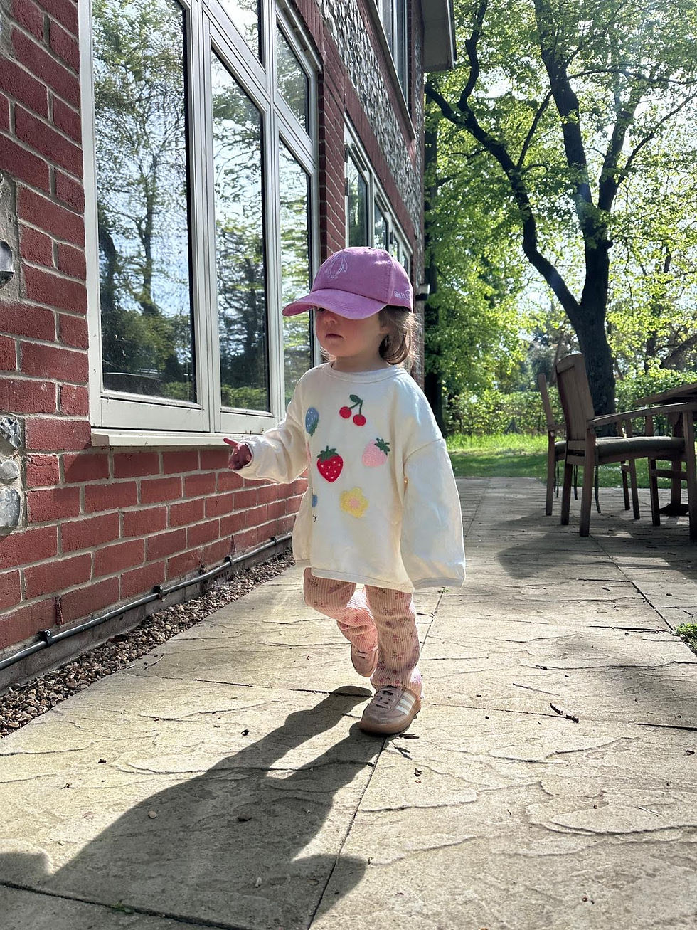 Pink Kids Cap embroidered with a penguin,  on a toddler playing outside