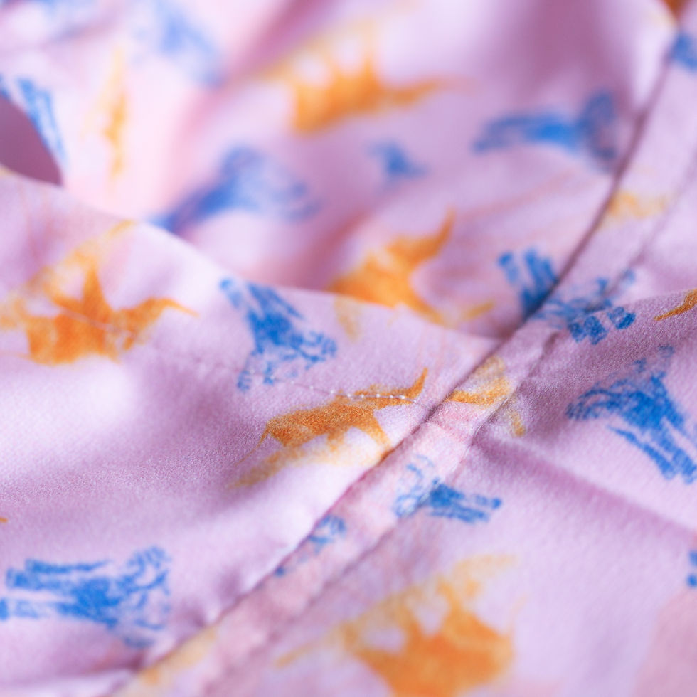 Thumbnail: a close up view of the stitching, seam and print of a towel poncho with little elephants on a pink background