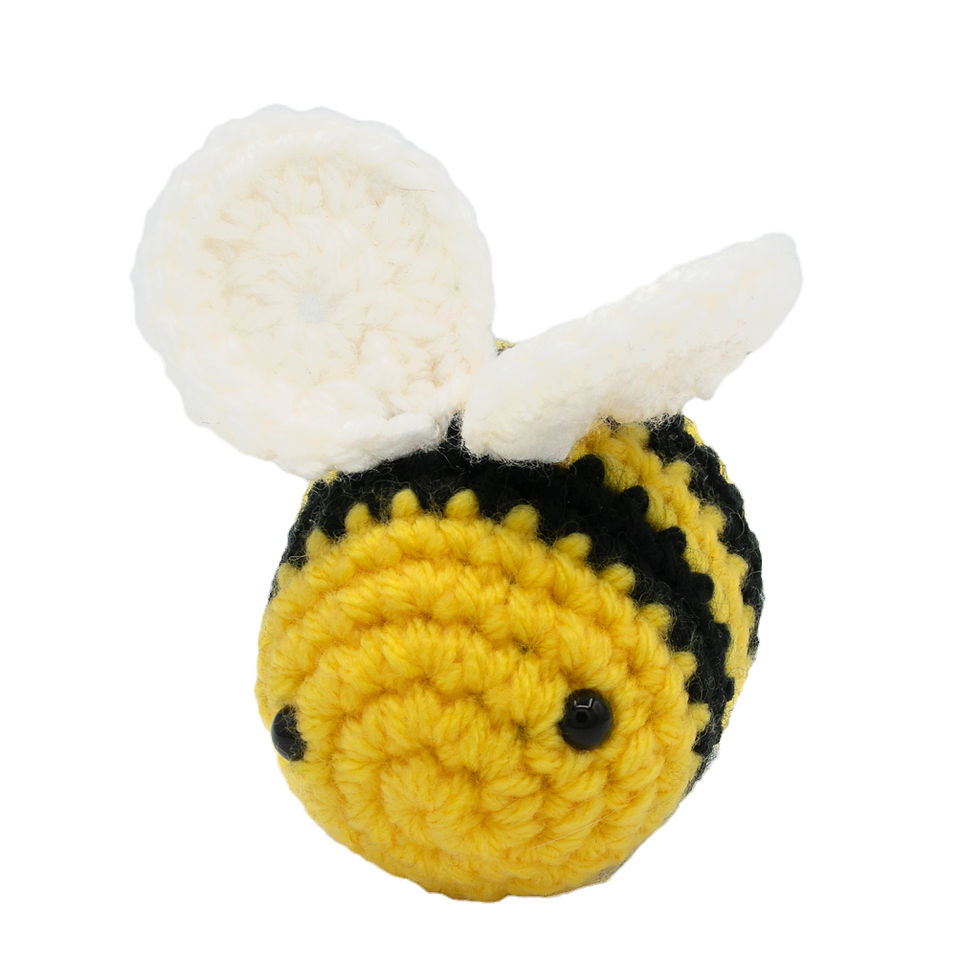 Close-up of Amigurumi Bee Plushie, black and yellow stripes, white wings on white background.