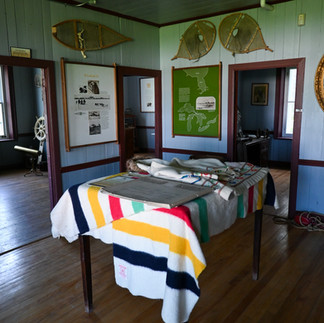 A table covered with the iconic striped HBC blanket, wooden snowshoes and other memorabilia on the wall