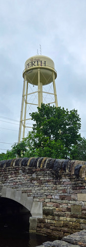 Water tower that says "Perth" behind a stone bridge in the foreground
