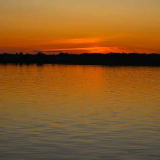 A view of the Moose River facing Moosonee at sunset, with the water gently rippled