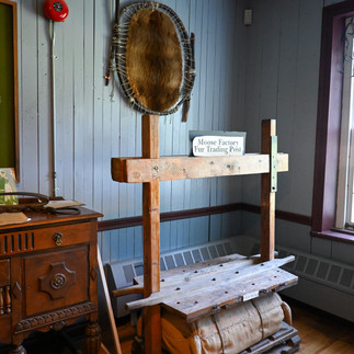 A sign saying "Moosonee Fur Trading Post" with objects from the fur trading era