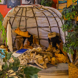 A recreation of an indigenous lean-to with replica people and many furs