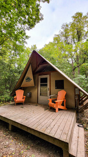 View of the outside of the oTentik accomodation, with two Muskoka chairs on the wooden platform porch