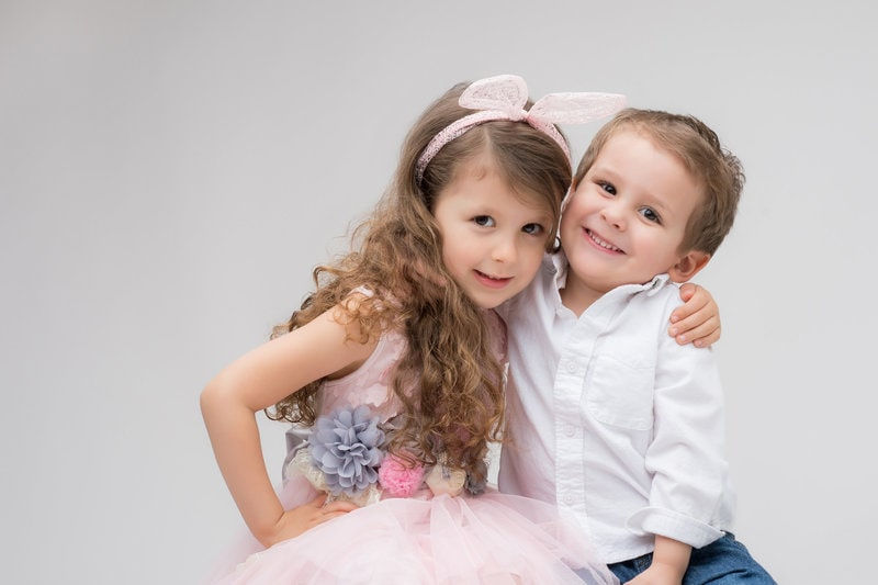 Two smiling kids posing together in colorful outfits.