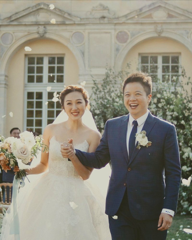 Couple walking out under falling petals at a chateau