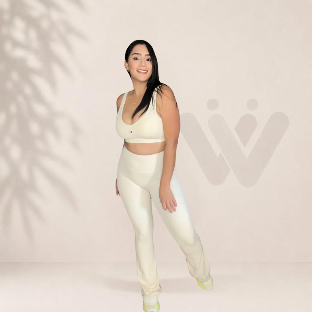 Mujer sonriente posando en conjunto deportivo color crema