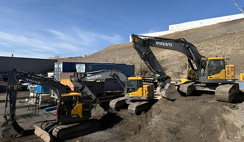 Three Volvo excavators work on a construction site 