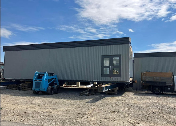 A farmhouse-style property is being moved on a trailer