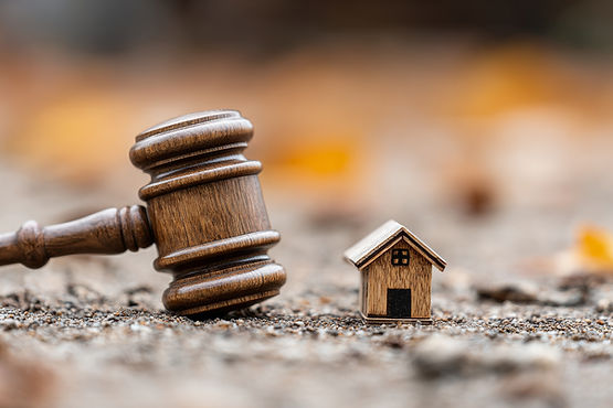 Wooden judge gavel beside miniature house