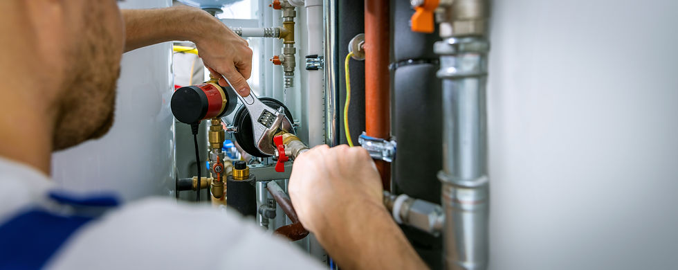 A plumber uses a wrench to adjust a red valve amidst a network of pipes