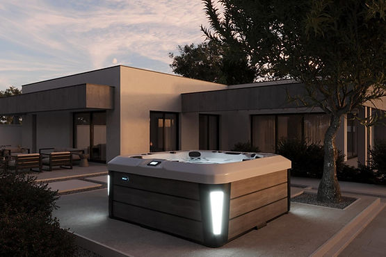 Outdoor jacuzzi at night beside a modern glass-walled house