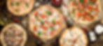 A table setting with five pizzas featuring various toppings, accompanied by dipping sauces and olive oil, ready to be served.