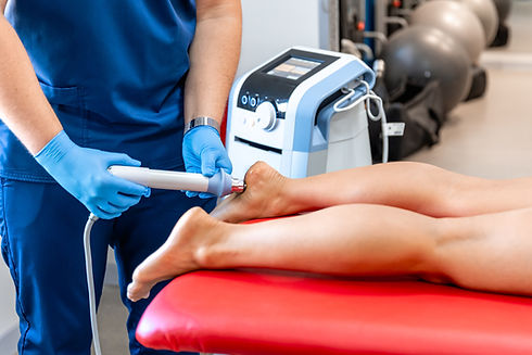 A therapist performs shockwave therapy on a patient's foot using a handheld device