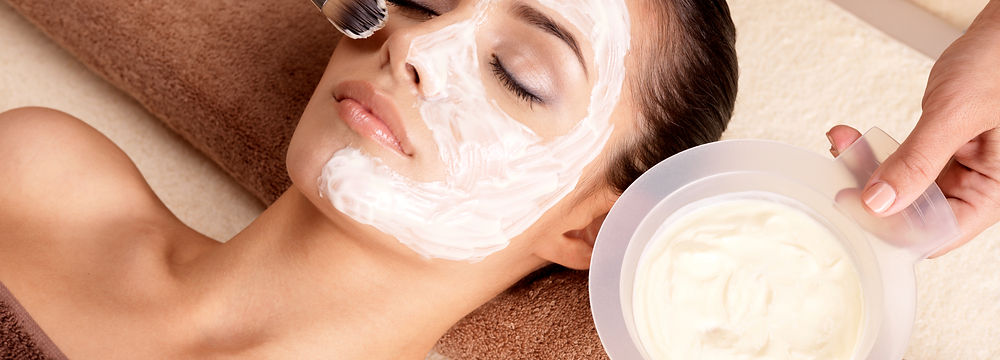 Woman receiving facial treatment with a white mask applied to her face