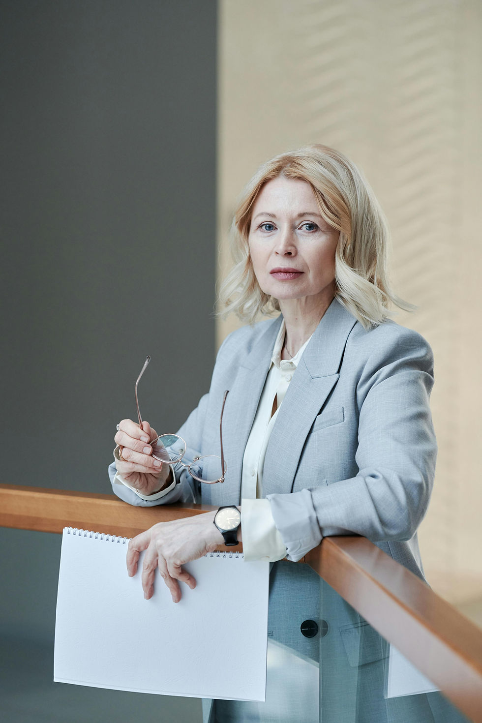 Confident businesswoman holding glasses and paper, corporate setting