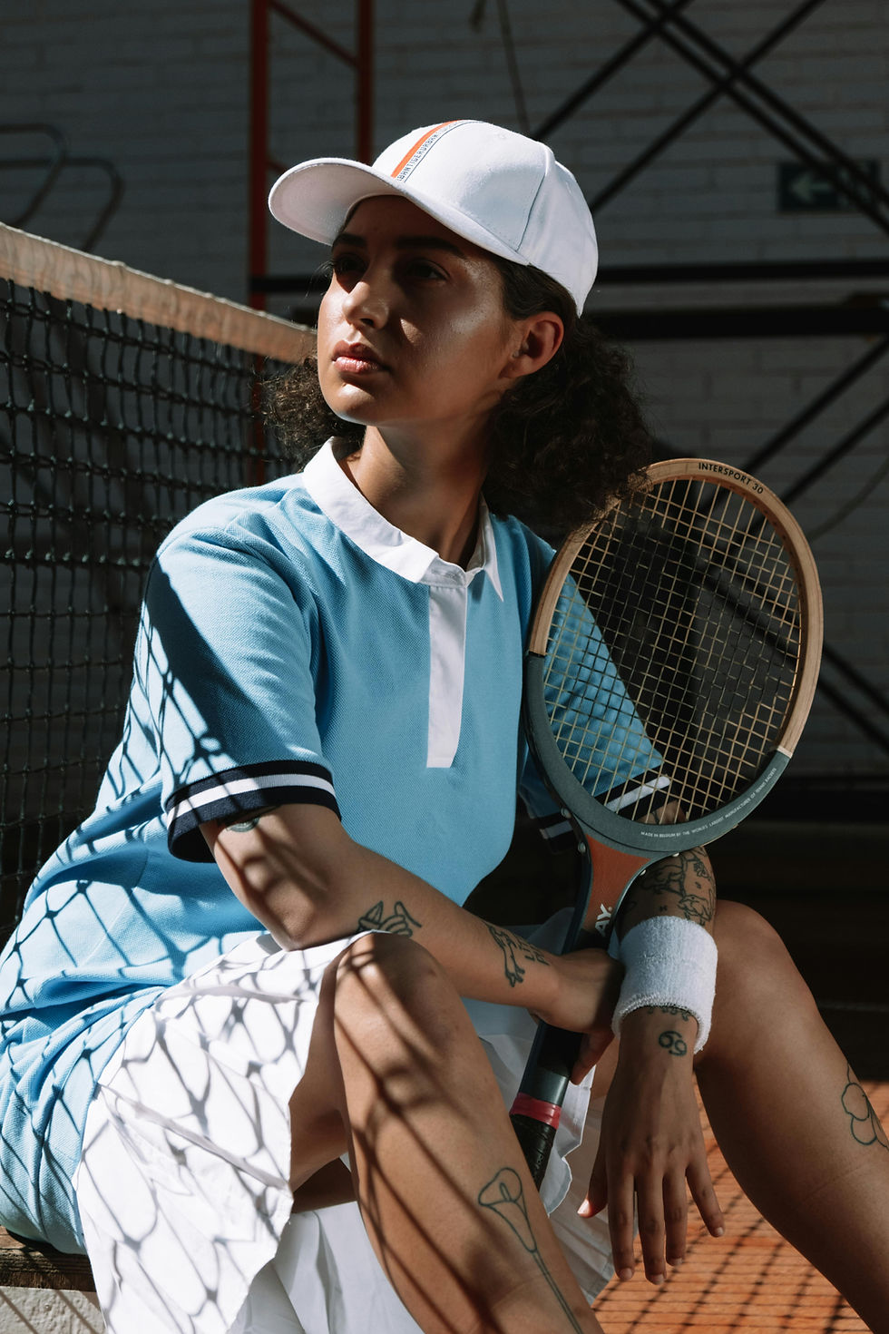 Woman in a blue tennis outfit, holding a tennis racket, sitting on a tennis court