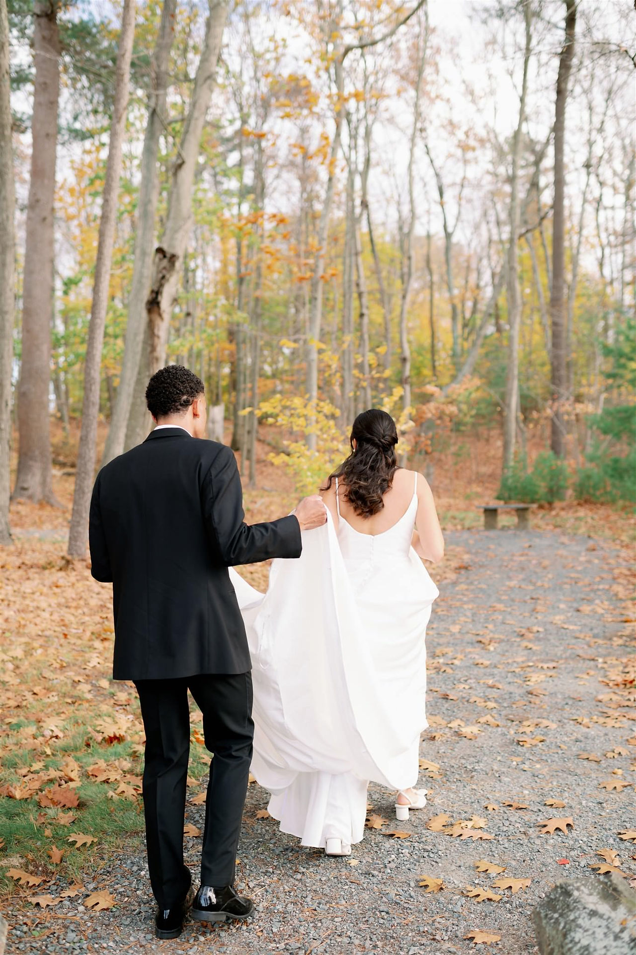 groom holding bride's train while they walk