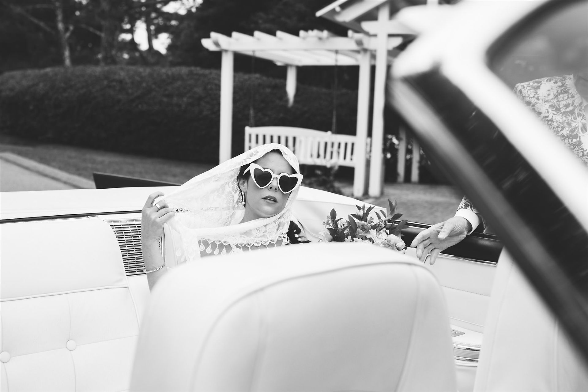 Bride arriving in convertible with heart sunglasses on 