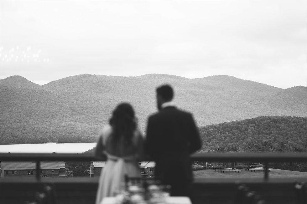 black and white photo with couple out of focus in the foreground with the focus on Vermont's Green Mountains in the distance
