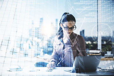 A young woman overlooking a laptop with a building and graphic digital overlay