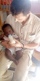 CAF volunteer in Uganda feeding baby